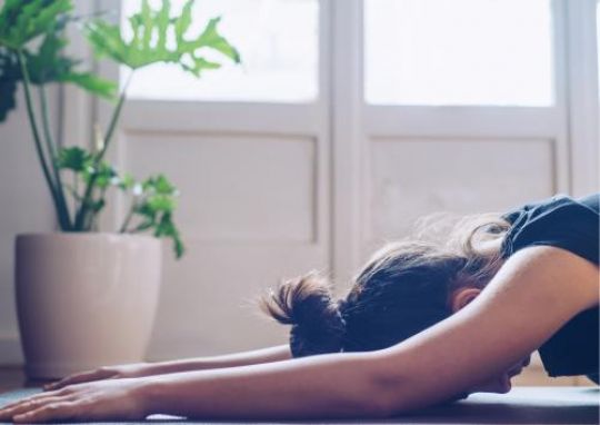 Oberkörper einer Frau auf dem Boden ausgestreckt in Yogapose.