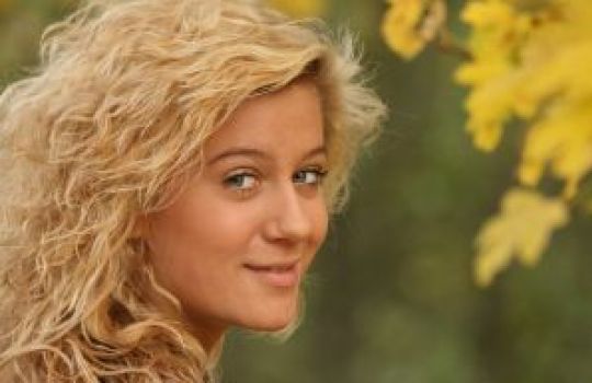 Eine junge blonde Frau dreht sich zum Betrachter um.