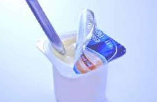Ein Löffel steckt in einem Becher Joghurt.