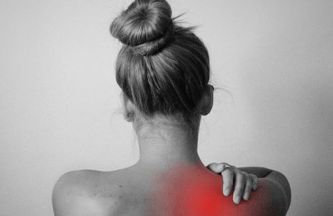 Person von hintern fotografiert, fasst sich an den Nacken