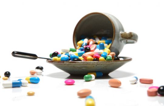 Auf einem kleinen Teller ist ein großer Haufen mit Tabletten und Pillen zu sehen.