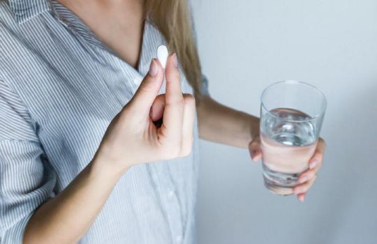 Frau nimmt Tablette ein: Bei der Traubensilberkerze sind einige Nebenwirkungen zu beachten. 