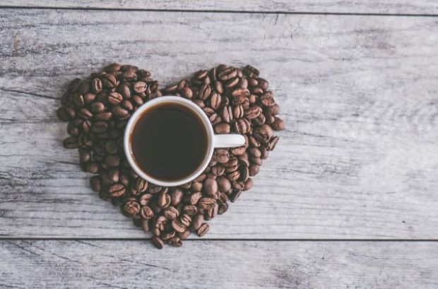 Kaffeetasse auf Herz aus Kaffeebohnen.