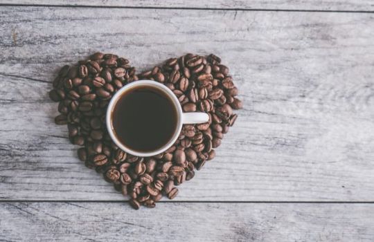 Kaffeetasse auf Herz aus Kaffeebohnen.