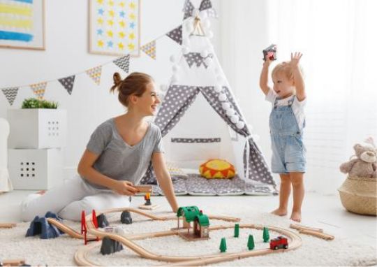 Frau und Kind im Kinderzimmer mit Spielzeug.
