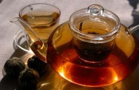 Gläserne Kanne und Glas, gefüllt mit Tee.