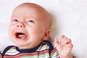 Ein Baby liegt schreiend auf einer Decke.