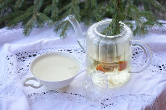 Kanne und Teetasse auf weißer Tischdecke