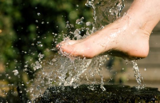 Ein Fuß wird mit Wasser begossen.