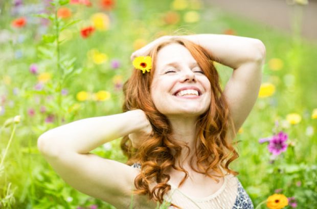 Eine junge Frau lächelt mit geschlossenen Augen.