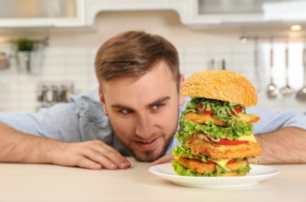 Junger Mann liebäugelt mit einem riesigen Burger.