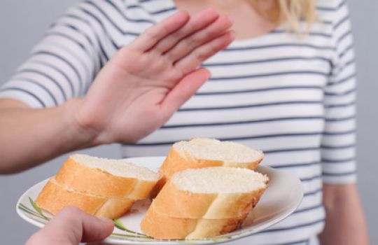 Ein Teller Brot wird einer Person angeboten, die diese mit einer Handgeste abwehrt.