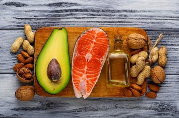 Avocado und Lachs, Öl und Nüsse auf einem Holzbrett, von oben fotografiert.