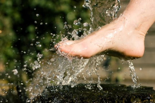 Nackter Fuß unter kaltem Wasserstrahl - so geht Kneippen.